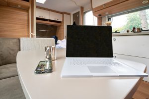 Homeoffice Arbeiten im Wohnwagen Wohnmobil mit Laptop und Internet im Urlaub unterwegs auf dem Campinglatz Homeoffice Arbeiten im Wohnwagen Wohnmobil mit Laptop und Internet im Urlaub unterwegs auf dem Campinglatz